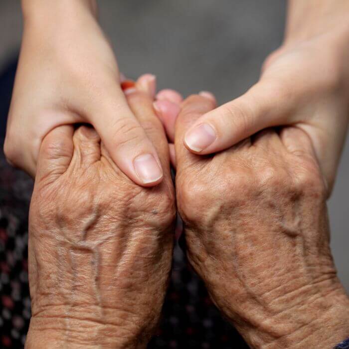 Younger hands holding an elderly persons hands reassuringly